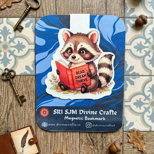 Cute baby raccoon reading Read Dream Thrive book magnetic bookmark by Sri SJM Divine Crafte on blue marble background